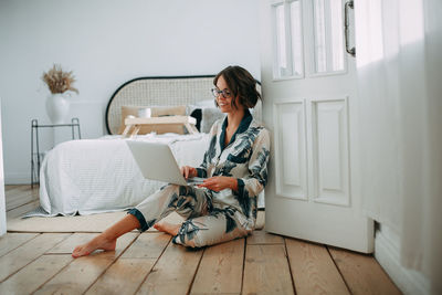 Young girl sitting on bed with laptop