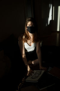 Portrait of woman wearing mask in darkroom
