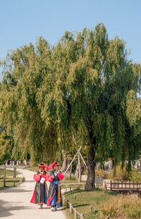 Rear view of people walking against trees