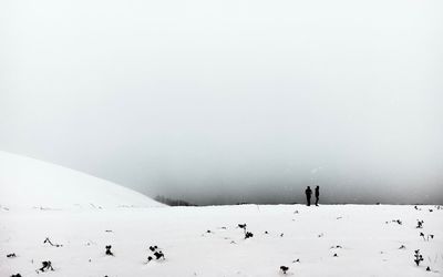 People walking on snow covered landscape against sky