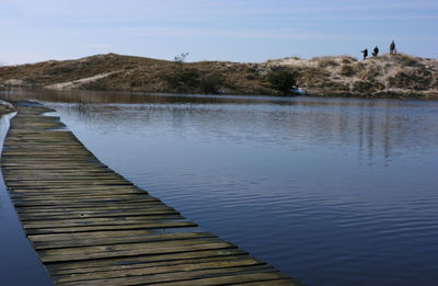 Wooden pier on lake against sky