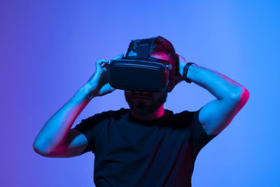 Young man wearing vr headset against colored background