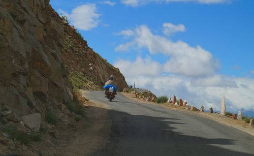 Man riding bicycle on road against sky