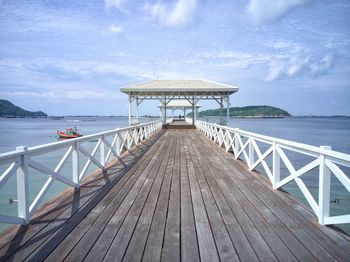 Diminishing perspective of pier over sea against sky during sunny day