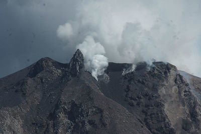 Smoke emitting from volcanic mountain against sky