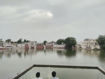 Scenic view of lake by buildings against sky