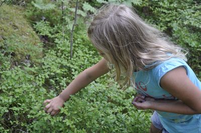 Side view of girl standing by plants