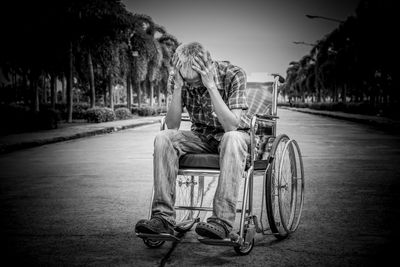 Depressed man with head in hands sitting on wheelchair