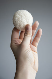 Close-up of hand holding apple against white background