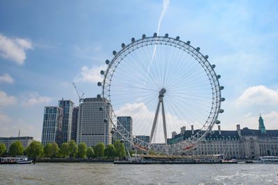 Ferris wheel in city against cloudy sky