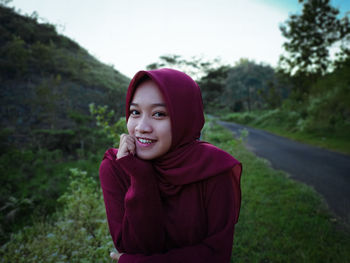 Portrait of smiling young woman standing on land