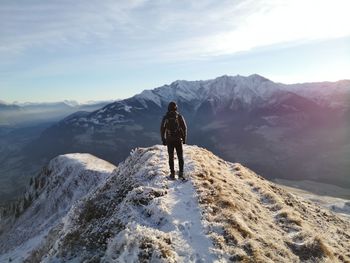 Rear view of person on snowcapped mountain against sky