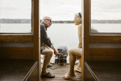 Happy senior couple talking while sitting at houseboat