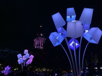 Illuminated christmas lights in city against sky at night