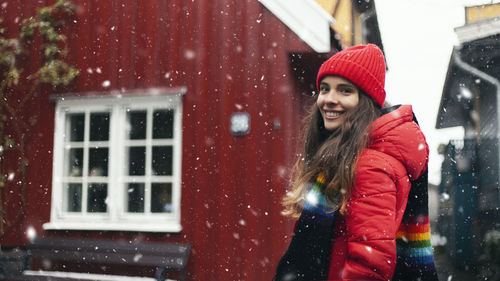 Portrait of smiling woman standing outside house during winter