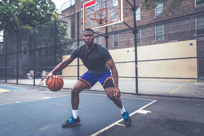 Portrait of young man practicing basketball in court