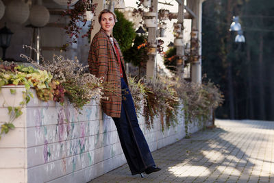 Beautiful fashion woman on street wearing stylish brown plaid coat, jeans and heeled boots.