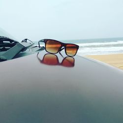 Close-up of sunglasses on beach against sky