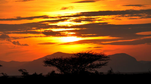 Scenic view of silhouette mountains against orange sky
