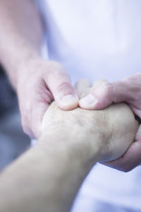 Midsection of doctor holding patient hand in hospital