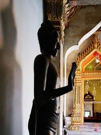 Statue of buddha against wall in building