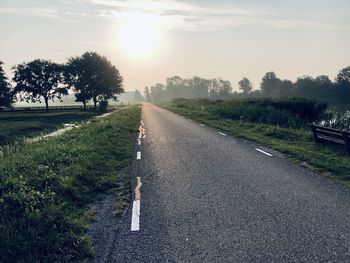 Road by trees against sky