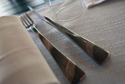 Close-up of fork and table knife by napkin on table