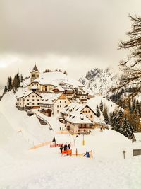 People skiing on snow covered field against sky