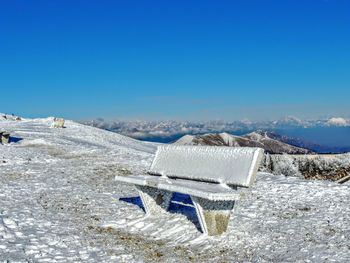 Snow covered land against clear blue sky