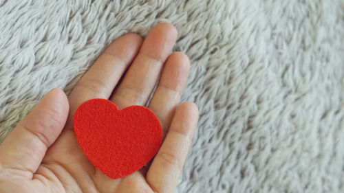 Cropped hand holding heart shape over rug