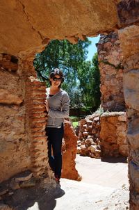 Young woman standing by old ruin during sunny day