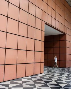 Full length of woman walking on tiled floor against building