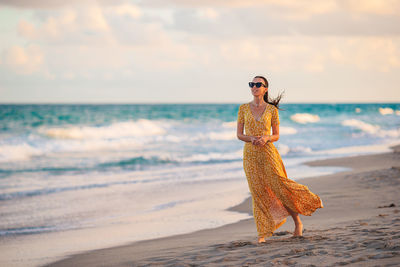 Full length of woman standing at beach against sky