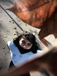 High angle portrait of woman seen through autumn leaf