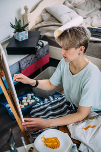 Young woman artist is painting at home in a creative studio setting.