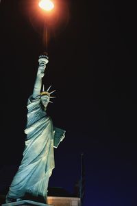 Low angle view of illuminated statue against sky at night