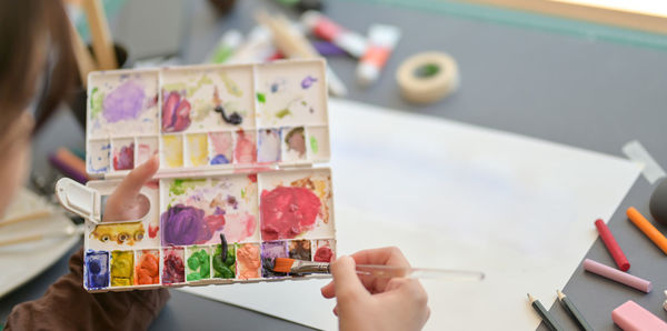 Midsection of person holding painting on table