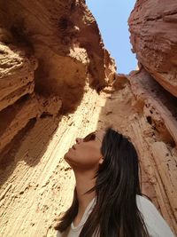 Low angle view of woman looking at rock formation