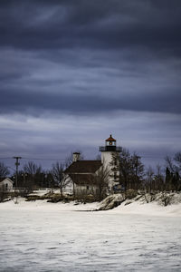 Lighthouse by sea against sky