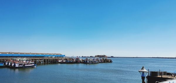 Ship moored at harbor against clear blue sky