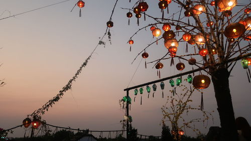 Lights in the dusk.   low angle view of illuminated lanterns hanging against sky at sunset