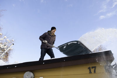 Man cleaning snow on house