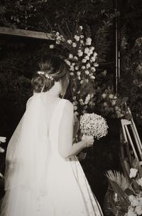 Rear view of woman standing by flowering tree