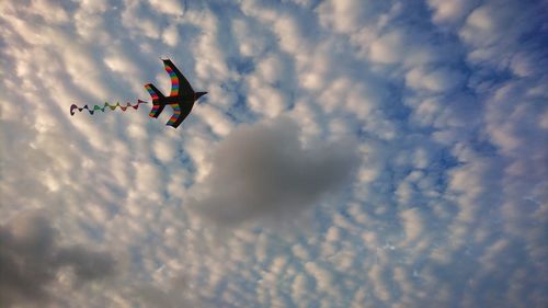 Low angle view of kite flying in cloudy sky