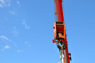 Crane hook on lifting gears and chains hanging of the mobile auto crane on a background blue sky