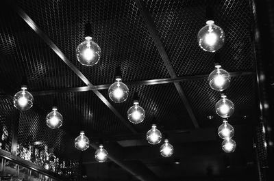 Low angle view of illuminated light bulbs hanging from ceiling