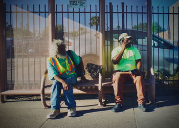 Men sitting on bench in city