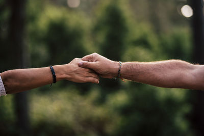 Cropped image of couple holding hands against trees