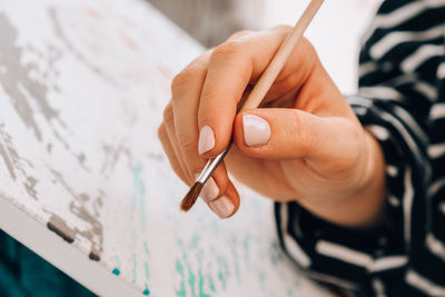 Painting on canvas by numbers and numbered jars of paint. woman draws with a brush painting 