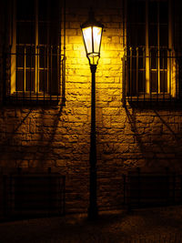 Illuminated street light against building